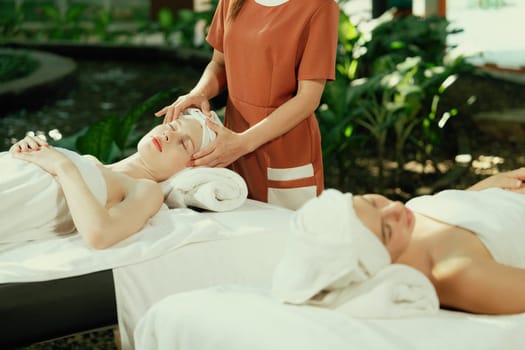 A portrait of two caucasian woman with beautiful skin having facial massage while falling the deep state of relaxation surrounded by outdoor natural and peaceful environment. Tranquility.