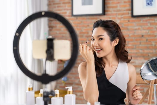 Asian Woman influencer shoot live streaming vlog video review makeup uttermost social media or blog. Happy young girl with cosmetics studio lighting for marketing recording session broadcasting online