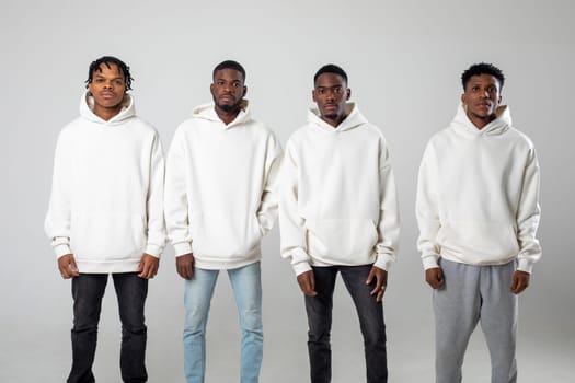 Group of African American guys in brown hoodies posing on a white background wearing sunglasses. High quality photo