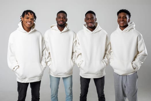 Group of African American guys in brown hoodies posing on a white background wearing sunglasses. High quality photo