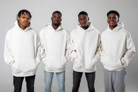 Group of African American guys in brown hoodies posing on a white background wearing sunglasses. High quality photo