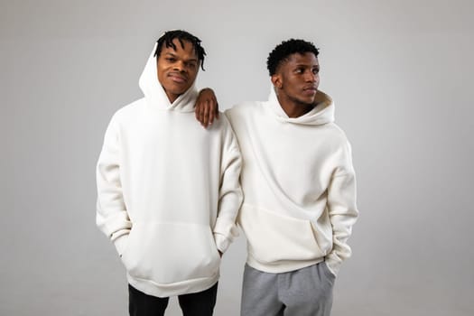 2 African American guys in white hoodies posing on a white background. High quality photo