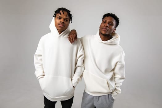 2 African American guys in white hoodies posing on a white background. High quality photo
