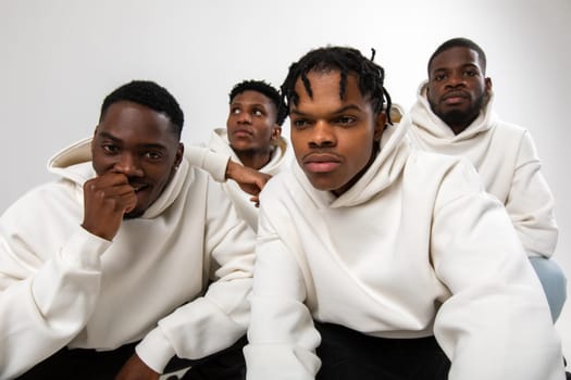 Group of African American guys in brown hoodies posing on a white background. High quality photo