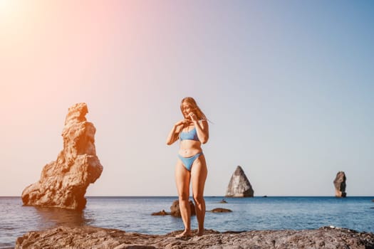 Middle aged well looking woman with black hair doing Pilates with the ring on the yoga mat near the sea on the pebble beach. Female fitness yoga concept. Healthy lifestyle, harmony and meditation.