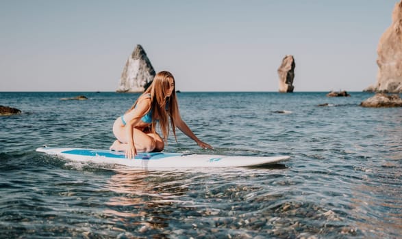 Close up shot of happy young caucasian woman looking at camera and smiling. Cute woman portrait in bikini posing on a volcanic rock high above the sea