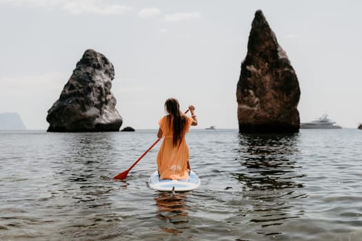 Close up shot of beautiful young caucasian woman with black hair and freckles looking at camera and smiling. Cute woman portrait in a pink bikini posing on a volcanic rock high above the sea