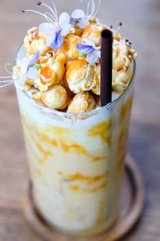 Iced caramel coffee with whipped cream and caramel popcorn on wooden table