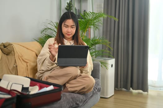 Young woman booking vacation trip or making hotel reservation on digital tablet. Travel and vacation concept.