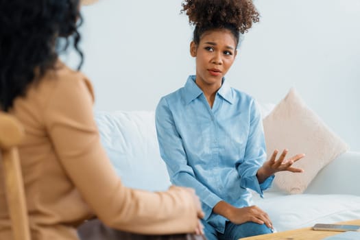 Sad PTSD woman patient in crucial therapy for mental health with psychologist, depression or grief after life failure. Frustrated trauma young woman talking to a psychologist about emotion in clinic