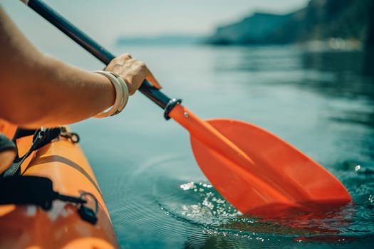 Kayak paddle sea vacation. Person paddles with orange paddle oar on kayak in sea. Leisure active lifestyle recreation activity rest tourism travel.