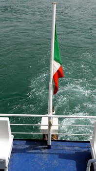 The rear flag of a ferry in Italy towards the Mediterranean islands.