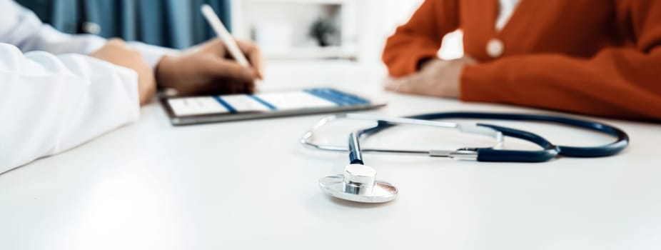 Focused stethoscope on office desk with blurred background of patient attending to doctor appointment at clinic or hospital discussing medical treatment or examining symptoms. Panorama Rigid