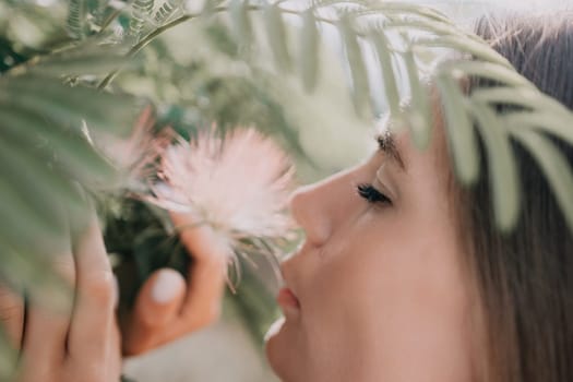 Beauty portrait of young woman closeup. Young girl smelling Chinese acacia pink blossoming flowers. Portrait of young woman in blooming spring, summer garden. Romantic vibe. Female and nature.