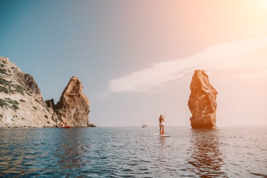 Close up shot of beautiful young caucasian woman with black hair and freckles looking at camera and smiling. Cute woman portrait in a pink bikini posing on a volcanic rock high above the sea