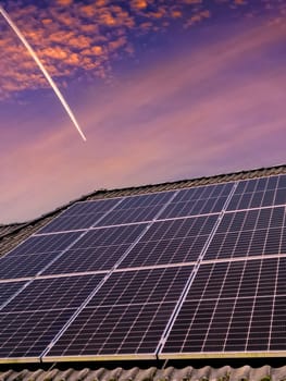 Solar panels producing clean energy on a roof of a residential house during sunset