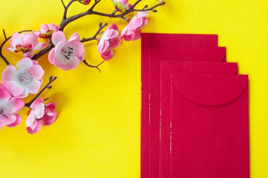 Top view of Chinese New Year red packet and cherry blossom decoration with customizable space for text or wishes. Chinese New Year celebration concept