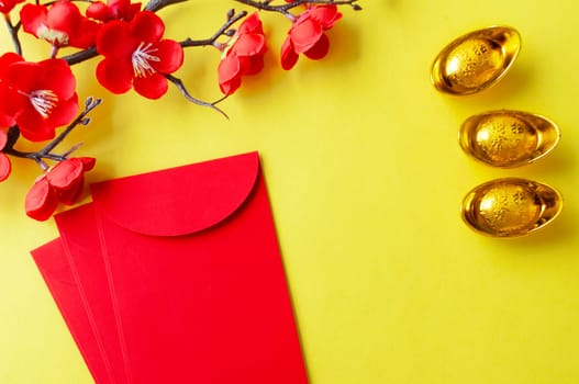 Top view of Chinese New Year red packet, cherry blossom and golden ingots decoration with customizable space for text or wishes.