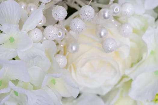 Gentle light background of white roses and beads. Close-up shooting, selective focus, soft focus
