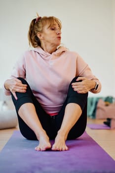 In a sunlit space, a senior woman gracefully practices rejuvenating yoga, focusing on neck, back, and leg stretches, embodying serenity and well-being.