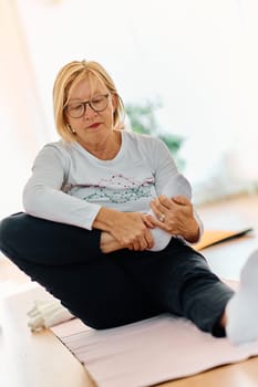 In a sunlit space, a senior woman gracefully practices rejuvenating yoga, focusing on neck, back, and leg stretches, embodying serenity and well-being.