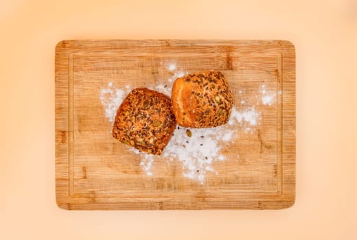 Baked rolls or fresh rolls with flour on a wooden cutting board