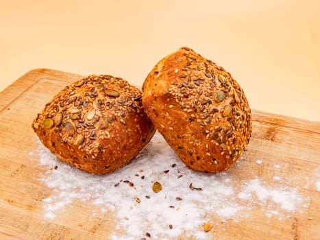 Studio shot with whole grain buns arranged on a board with flour fresh for breakfast