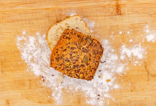 Home-baked German grain rolls fresh from the bakery arranged with flour on a wooden board photographed directly from above
