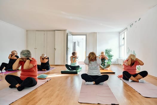 A group of senior women engage in various yoga exercises, including neck, back, and leg stretches, under the guidance of a trainer in a sunlit space, promoting well-being and harmony.