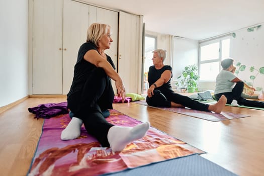 A group of senior women engage in various yoga exercises, including neck, back, and leg stretches, under the guidance of a trainer in a sunlit space, promoting well-being and harmony.