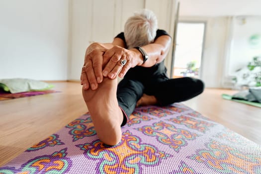 An elderly woman gracefully engages in various yoga poses, stretching her limbs and finding serenity in a modern sunlit space under the guidance of a trained instructor, embodying the essence of active and mindful aging.