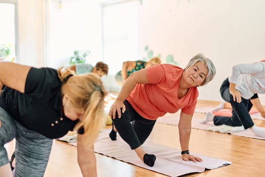 A group of senior women engage in various yoga exercises, including neck, back, and leg stretches, under the guidance of a trainer in a sunlit space, promoting well-being and harmony.