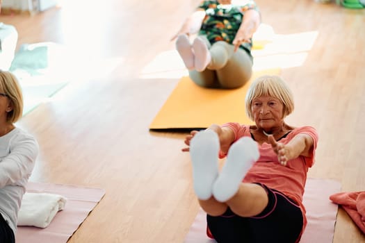 A group of senior women engage in various yoga exercises, including neck, back, and leg stretches, under the guidance of a trainer in a sunlit space, promoting well-being and harmony.