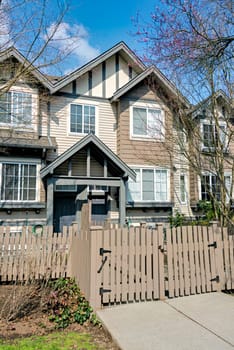 Residential townhouse entrance with wooden fence in front on early sprint day in Vancouver, Canada