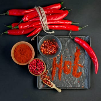 Red chili pepper cut into pieces on a black background.