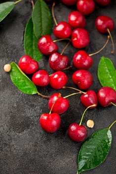 Ripe sweet cherry berry with leaves on a black wooden