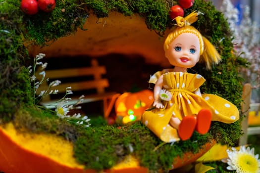 A small doll in a fairy house made of squash.
