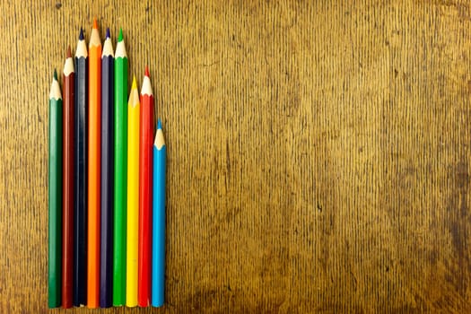 Several colored pencils on a wooden background. Copy space.
