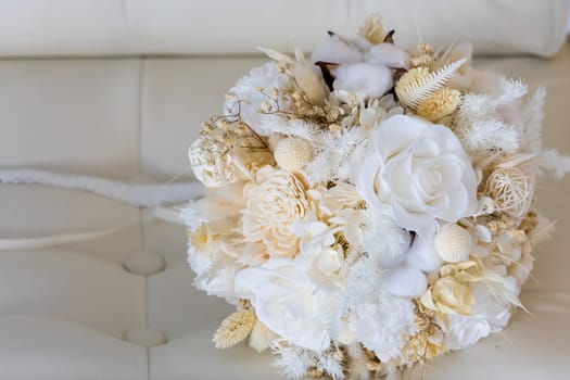 A tender bouquet of the bride in pastel colors on a leather sofa.