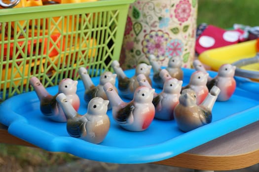 Many children's ceramic whistles in the shape of a bird on a tray.