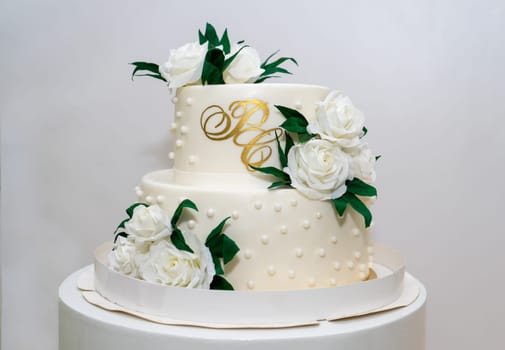 Two-tiered white wedding cake decorated with white roses.