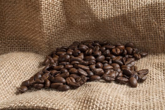 Brown roasted coffee beans on sackcloth.