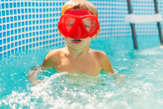 A joyful child sporting red goggles is half-submerged in a swimming pool, ready for aquatic adventures on a bright, sunny day.