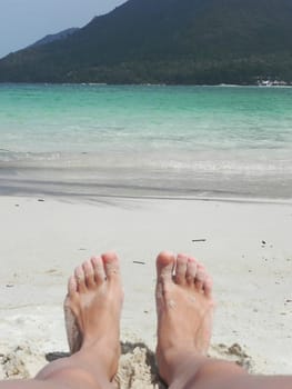 beautiful legs of a beautiful girl on the sand by the sea.