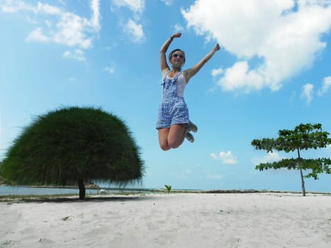 Young beautiful woman jumping in the beach