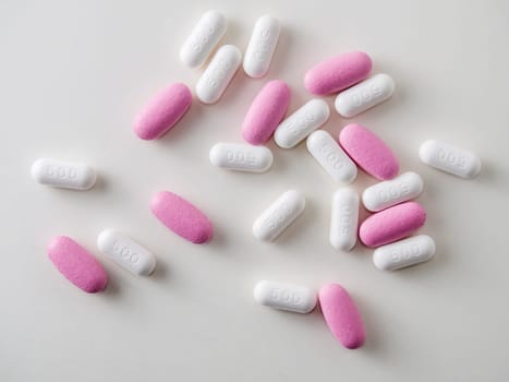 multicolored medical pills and packs of pills on a white table.