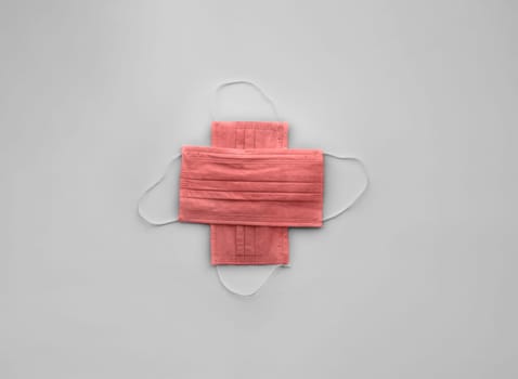 Red medical protective masks cross shape on white with copy space