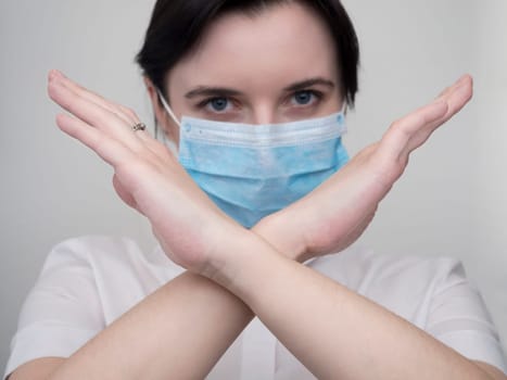 Masked woman makes stopping hand gesture. Stop coronavirus or covid 19 outbreak concept
