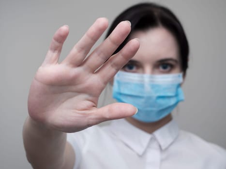 Masked woman makes stopping hand gesture. Stop coronavirus or covid 19 outbreak concept