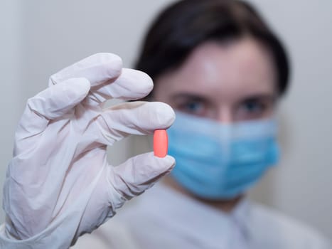 Doctor giving pills, woman in medical mask and gloves. The concept of the dose of drugs, vitamins, medical examination, coronavirus, treatment of influenza